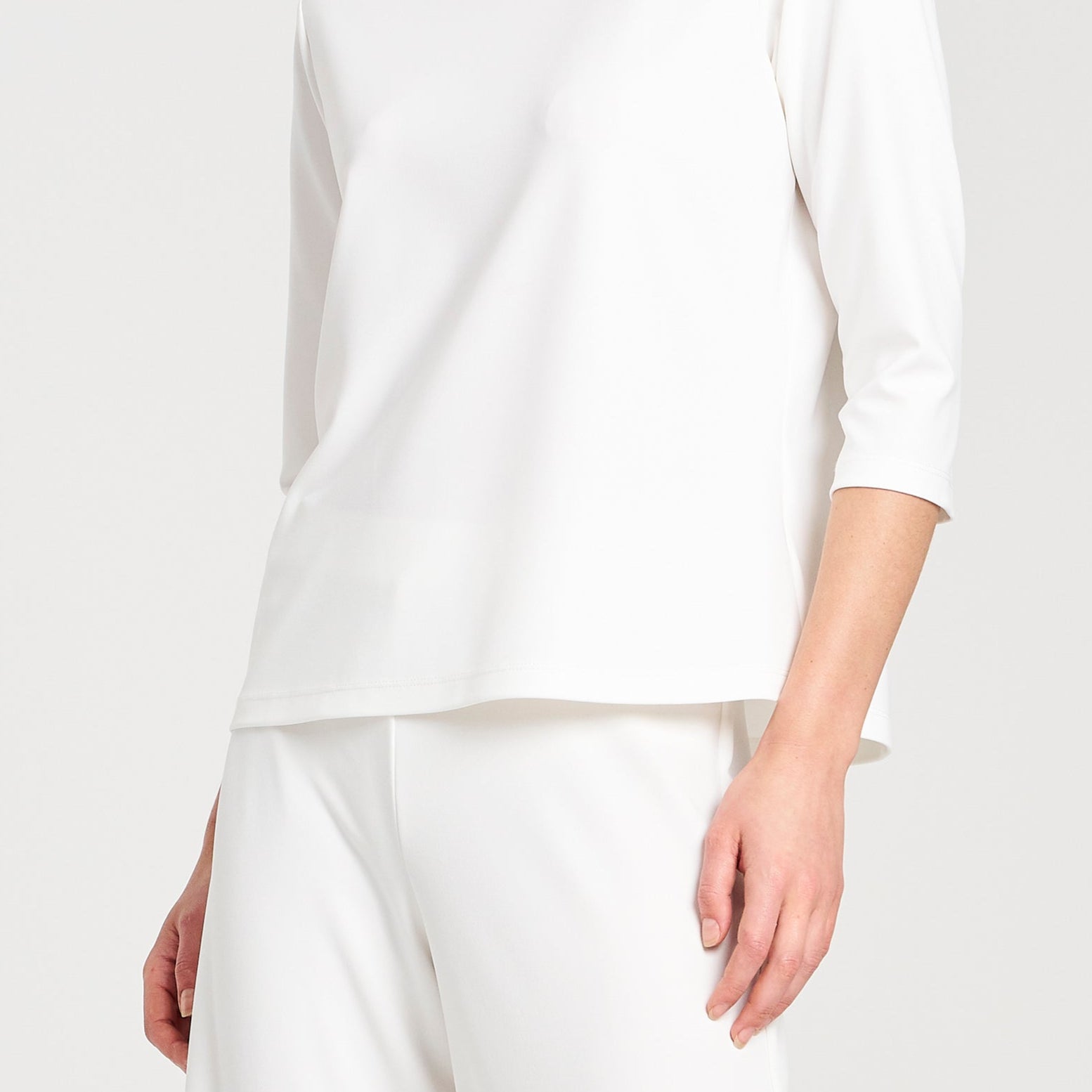 Person wearing a white long-sleeve top and pants on a white background