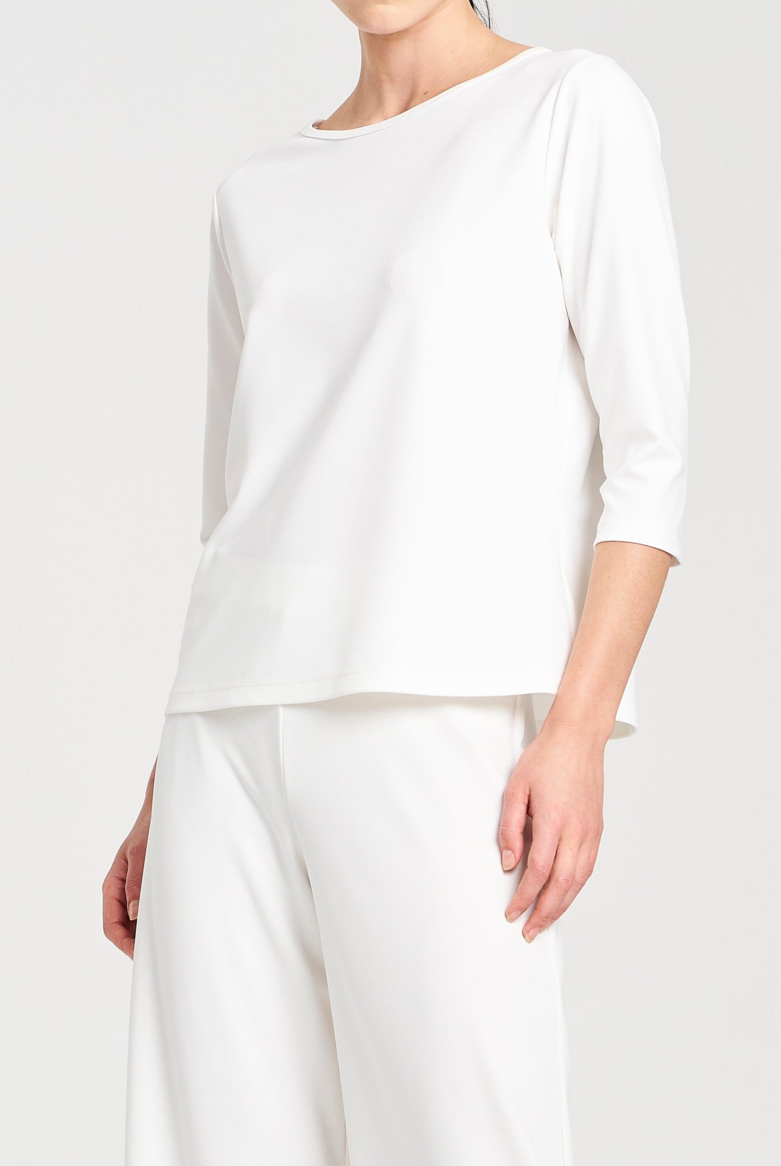 Person wearing a white long-sleeve top and pants on a white background