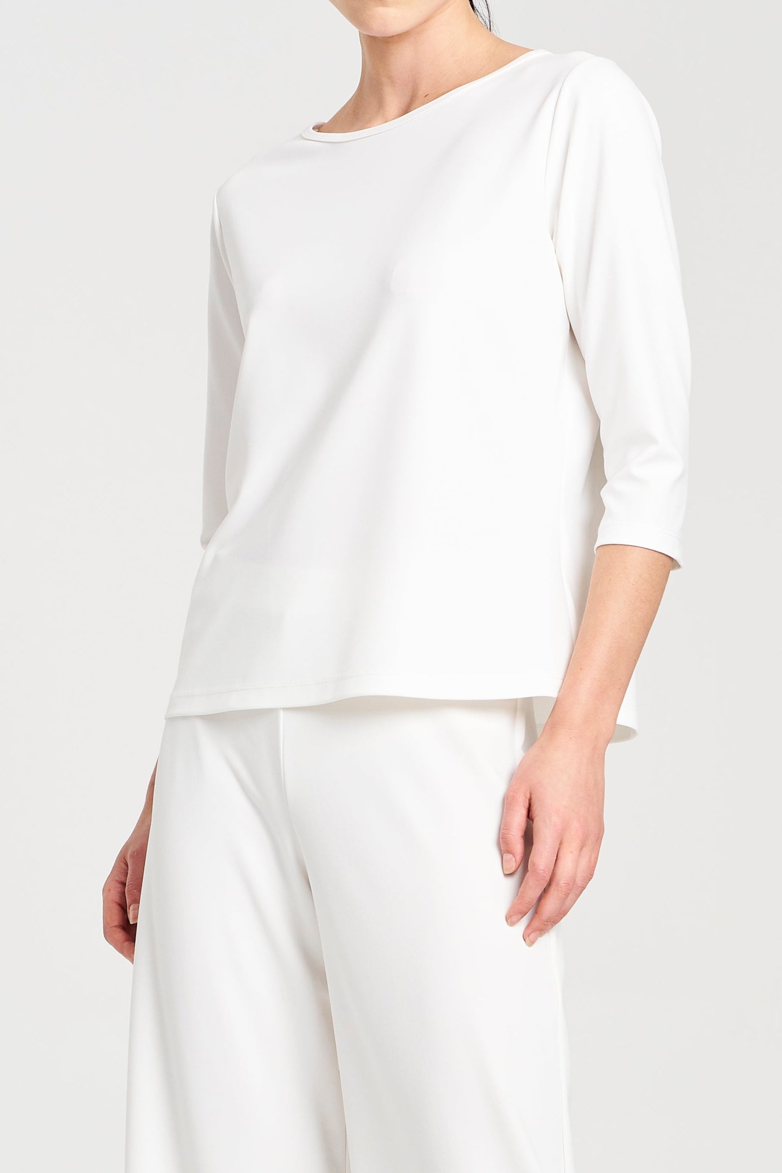 Person wearing a white long-sleeve top and pants on a white background
